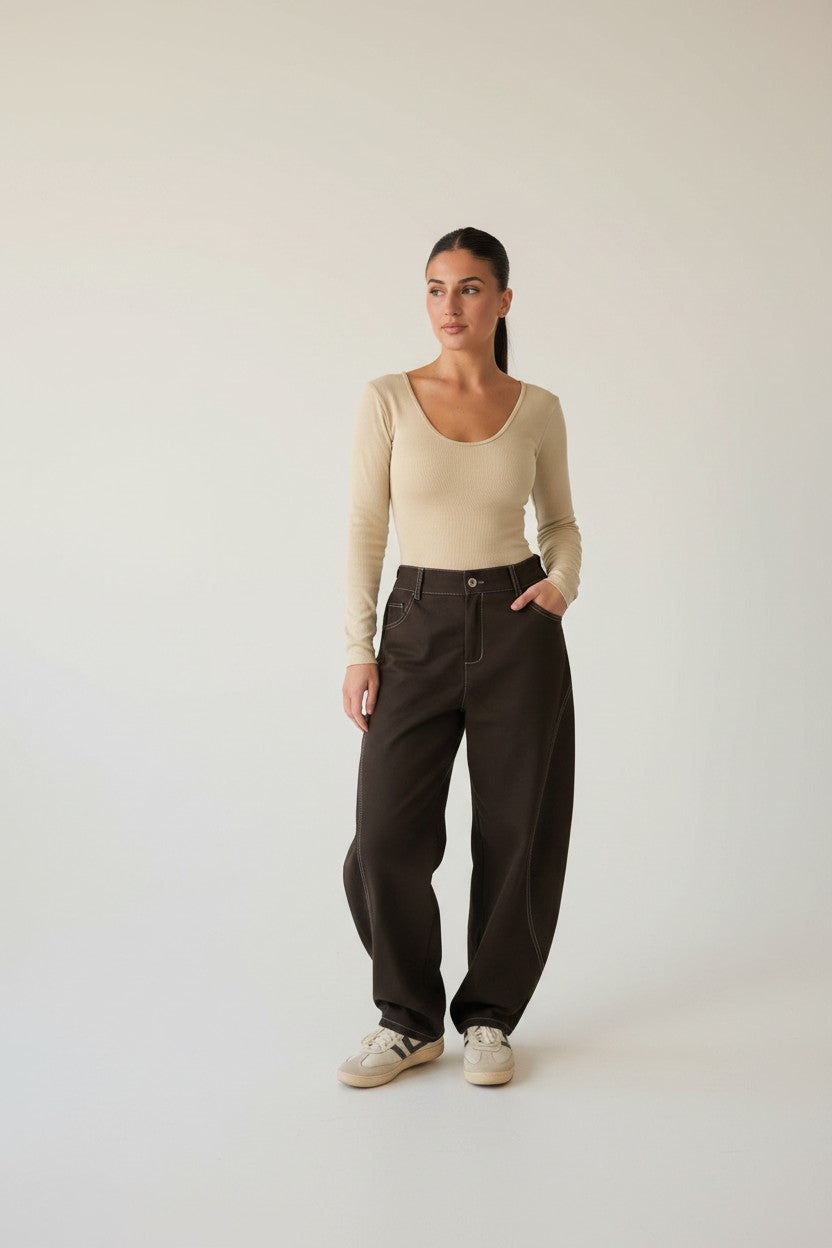 Femme portant le pantalon ballon surpiqué chocolat, jambe arrondie resserrée à la cheville