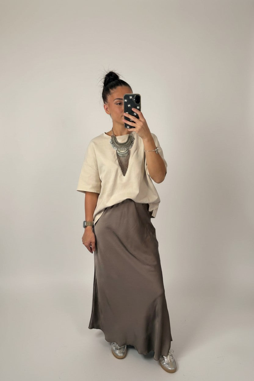Femme portant la jupe longue satinée taupe avec un t-shirt écru ample