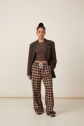 Femme portant le pantalon large à carreaux bordeaux avec un blazer marron ouvert