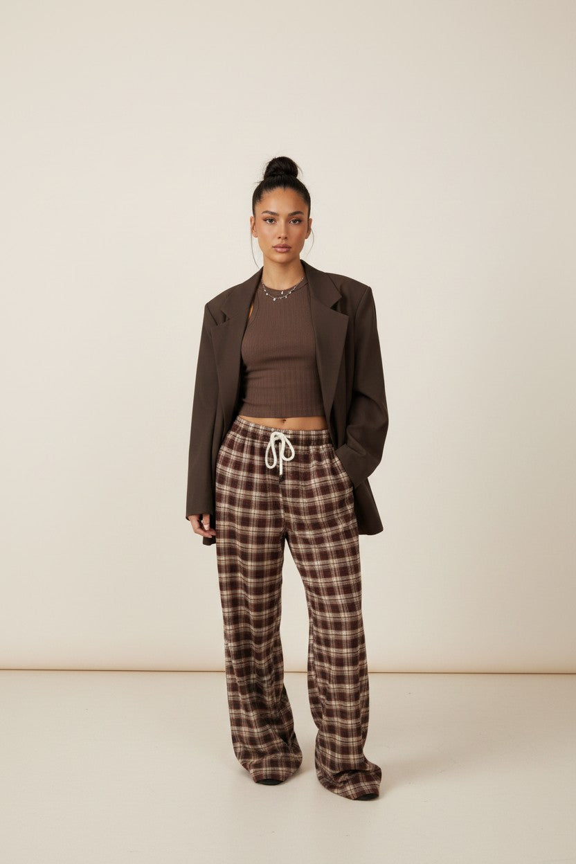 Femme portant le pantalon large à carreaux bordeaux avec un blazer marron ouvert